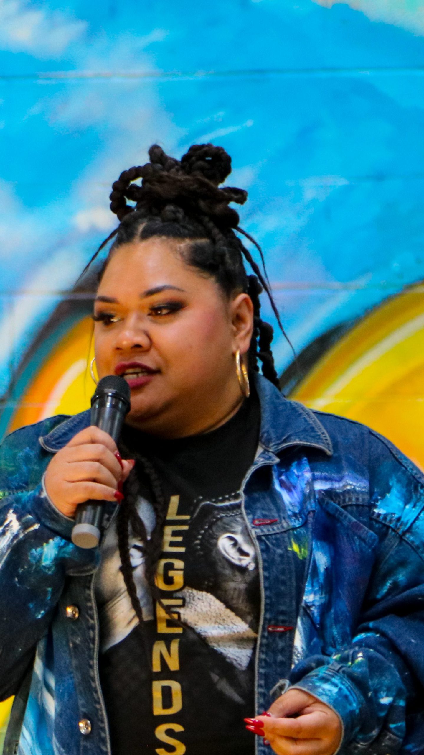 Tracy Williams presenting with a bright mural behind her. 