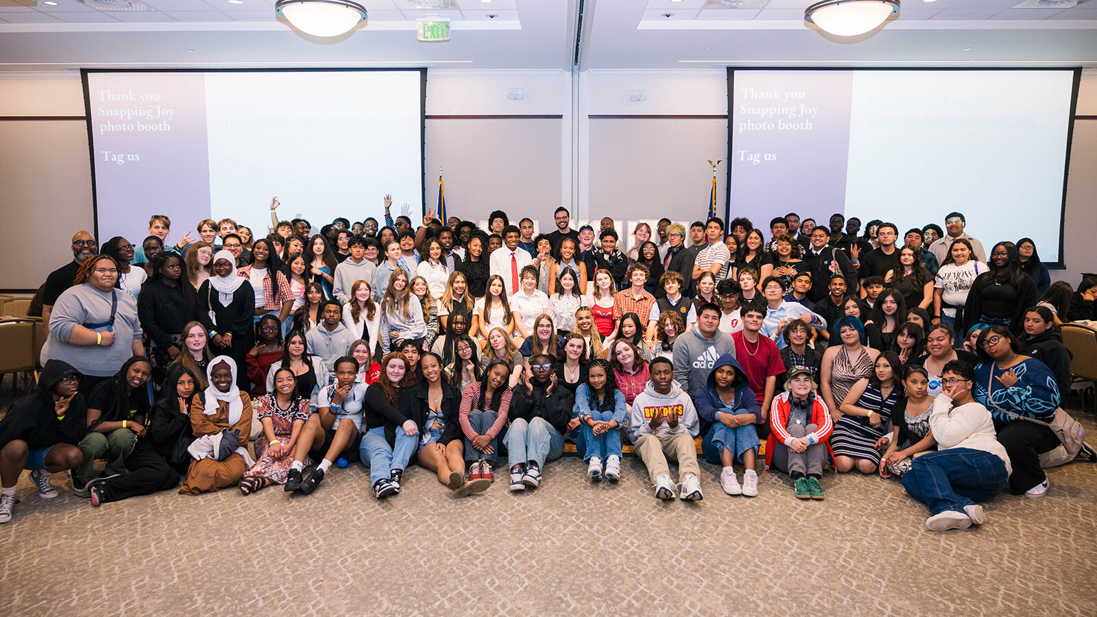 Large group of diverse students posing together in a conference room for a group photo.