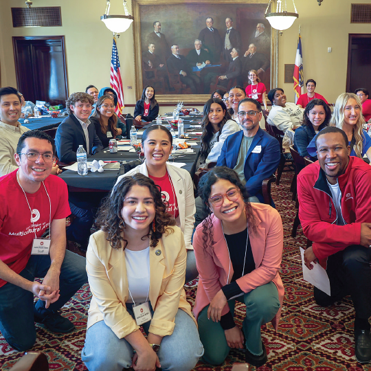 A diverse group of people posing for a photo in a conference room.